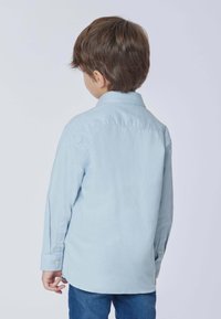 Camicia azzurro chiaro con bottoni, maniche lunghe, colletto e orlo curvo. Tessuto leggero con una consistenza liscia, mostrata da dietro.