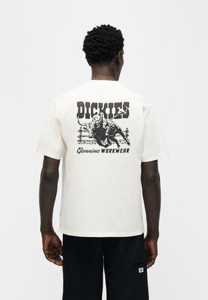 Person wearing white t-shirt with black graphic of a bull jumping over a fence and text "Dickies Genuine Workwear" on the back.