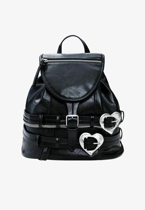 Zwarte leren rugzak met een afgeronde flap, zilverkleurige rits, hartvormige accenten en verstelbare bandjes. Heeft meerdere gespdetails.