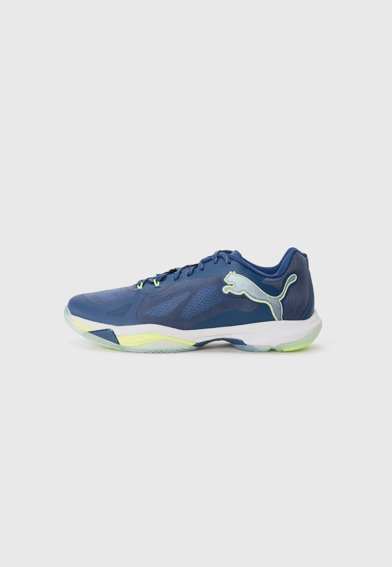 Kék sportcipők hálós felsőrésszel, lime zöld kiegészítőkkel és fehér középtalppal. Puma logóval és karcsú designnal a teljesítmény érdekében.