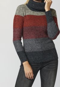 Pull en tricot avec un col roulé haut, présentant des rayures horizontales dans des tons rouge, gris et gris foncé. Tissu texturé et côtelé.
