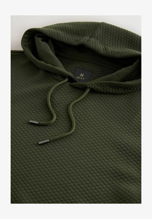 Vihreä tilkkuuntunut huppari, jossa on tekstuuripinta, varustettuna nyörillä, jossa on metalliset päät, sekä etiketti ommeltuna kauluksen lähelle.