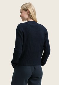 Navy blue knitted sweater with a textured pattern and ribbed cuffs. The design features a round neckline and a fitted bottom hem.