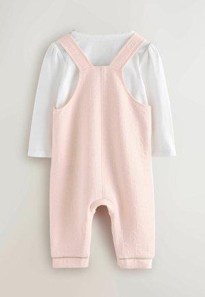 Completo in maglia rosa con un discreto motivo in rilievo a forma di "B", dotato di spalline regolabili e una camicia bianca a maniche lunghe sotto.