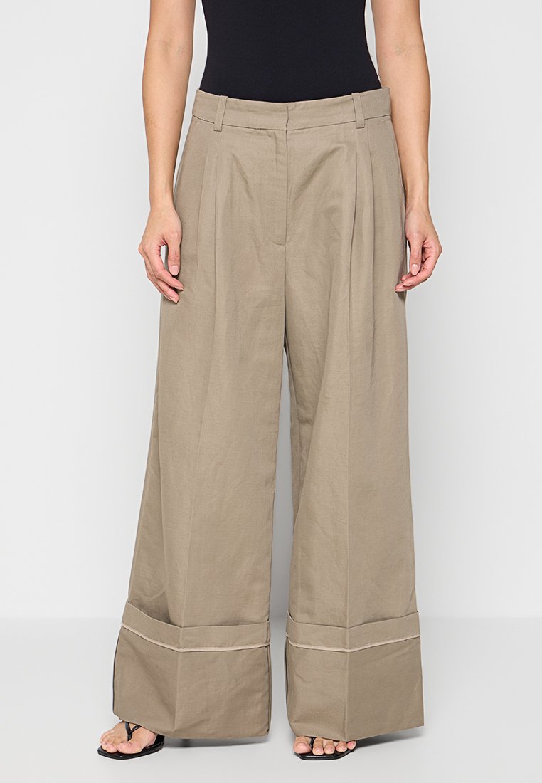 Beige wijde pantalon met een hoge taille, voorplooien en grote manchetten. Gemaakt van lichte stof, met een schone, eenvoudige uitstraling.