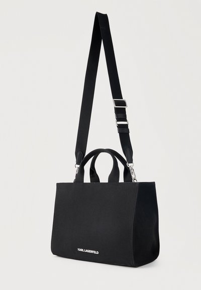 Черна правоъгълна дамска чанта с къси дръжки и регулируема дълга презрамка за през рамо, с малко бяло лого „KARL LAGERFELD“.