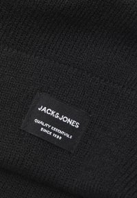 Crna pletena kapa s teksturiranim uzorkom. Ima pravokutnu oznaku branda bijelog teksta s natpisom "JACK & JONES QUALITY ESSENTIALS SINCE 1990."