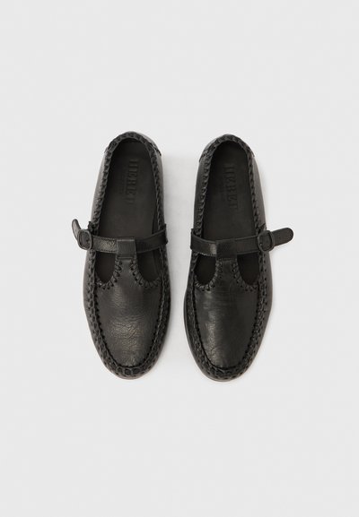 Pantofi negri din piele cu finisaj texturat, având un vârf rotunjit, părți laterale decupate și o curea cu cataramă, cu detalii cusute pe talpă.