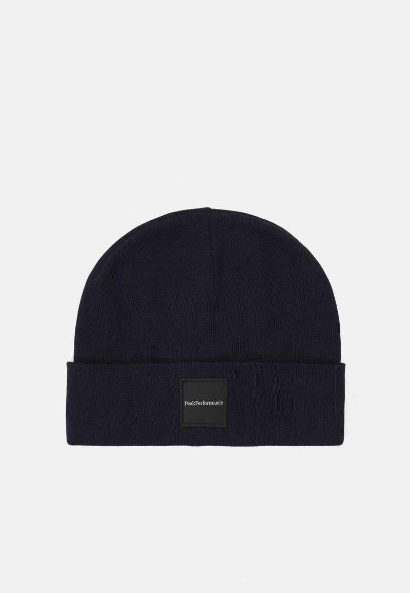 Dark navy beanie made of ribbed knit material. Features a folded cuff and a square black patch labeled "Peak Performance." Simple and functional design.