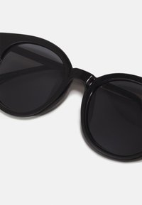 Ochelari de soare negri cu rame mari, rotunjite și lentile închise. Material din plastic neted, lucios, fără hardware sau detalii vizibile.