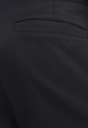 Black trousers made of textured fabric featuring a rear pocket and a subtle Nike logo in black on the right side.