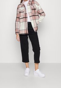 Ruudullinen takki vaaleanpunaisen, valkoisen ja mustan sävyissä, jossa kaksi rintataskua, yhdistetty mustiin lyhytlahkeisiin housuihin ja valkoisiin tennareihin. Sileäpintainen, rento malli.