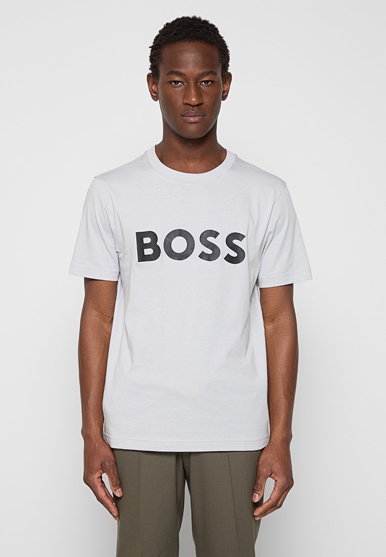 Camiseta de algodón gris con un gran logo negro "BOSS" en el frente, cuello redondo y mangas cortas, con un corte relajado.