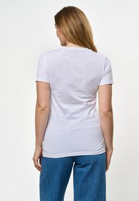Hvit bomulls t-skjorte med korte ermer, tilpasset design, jevn tekstur og rund hals, kombinert med løse blå jeans.