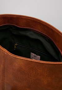 Borsa a tracolla in pelle marrone con superficie testurizzata, dotata di fodera in tessuto nero e una piccola tasca con zip all'interno.