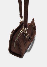 Brun ruskind håndtaske med guldfarvet hardware, lynlås-lukning og justerbar skulderrem. Har eksterne lommer og en struktureret form.