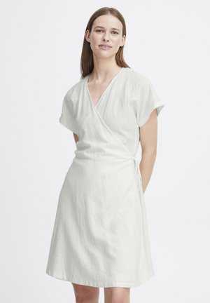 Robe enveloppante en lin blanc à manches courtes et décolleté en V, avec un lien sur le côté et un ourlet légèrement évasé. Texture lisse.
