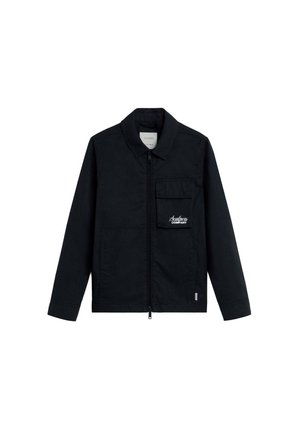 Chaqueta negra de manga larga con collar, cremallera frontal, bolsillo con solapa en el pecho con el logo "Scalpers Company" y dos bolsillos frontales inferiores.