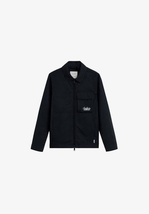 Chaqueta negra de manga larga con collar, cremallera frontal, bolsillo con solapa en el pecho con el logo "Scalpers Company" y dos bolsillos frontales inferiores.