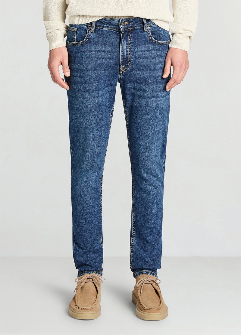 Jean en denim bleu avec une coupe droite, présentant un design traditionnel à cinq poches, des coutures visibles et une taille mi-haute.