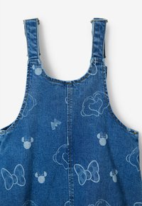 Monos en denim de color azul oscuro con un sutil patrón de lazos azul claro, cabezas de ratón y rayos, que presentan tirantes ajustables y herrajes de botón.