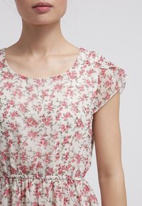 Květinové šaty s růžovými vzory růží na světlém pozadí. Mají krátké, průhledné rukávy a elastický pas. Měkká, lehká tkanina.