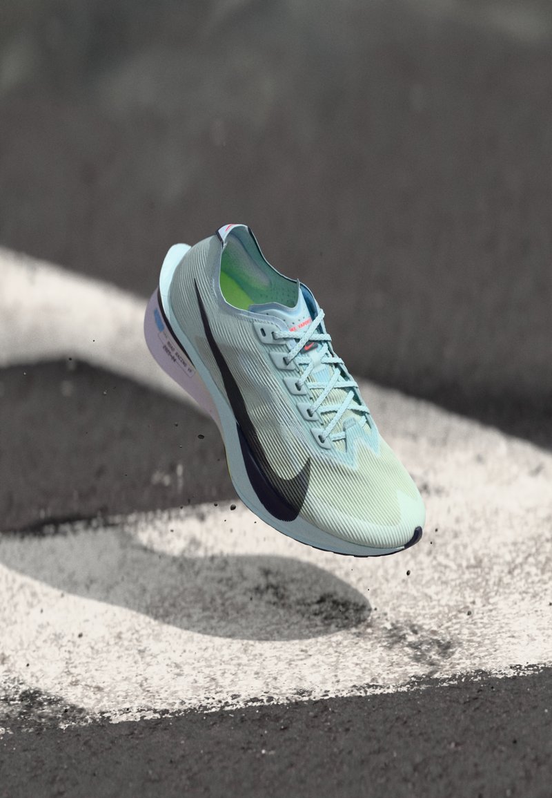 Baskets de course bleu clair avec texture striée, logo swoosh noir, lacets fins et amorti souple visible sur la semelle.