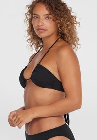 Zwarte bikini-top met driehoekige cups, geplooide details, dunne bandjes en een eenvoudige sluiting in het midden. De stof lijkt glad en mat.