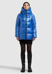 Blå dunjacka med hög krage, dragkedja och justerbara dragskor. Slätt, glänsande material med quiltat mönster.
