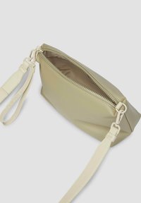 Prostokątna torba na ramię w jasnozielonej sztucznej skórze, z zamkiem błyskawicznym, regulowanym paskiem i gładką fakturą. Wnętrze jest w kolorze beżowym.
