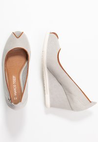 Scarpe a zeppa grigie con una parte superiore texturizzata e accenti marroni. Il design presenta una punta arrotondata e un pannello laterale in suede liscio.