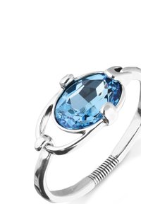 Anillo de plata con una gran piedra preciosa azul ovalada. La piedra preciosa presenta facetas y un engaste de garras, banda texturizada con una sección en espiral.