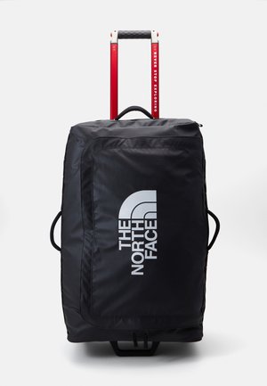 Borsa da viaggio nera con manico rosso retrattile. Presenta un grande logo frontale, cerniere e maniglie laterali per un facile sollevamento e trasporto.