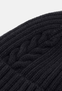 Fekete kötött sapka bordás textúrával és fonott mintával, puha gyapjú anyagból készült, amely a meleget és a részletgazdagságot mutatja.