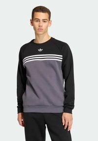 Čierna a sivá mikina s okrúhlym výstrihom, raglánovými rukávmi, tromi bielymi pruhmi cez hruď a malým logom pri výstrihu.