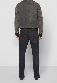 Zwarte denim jeans met een rechte pasvorm en een vijf-pocket ontwerp, gecombineerd met een donkere, vervaagde sweatshirt met ribgebreide boorden en een halslijn.