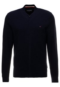 Mörkblå zip-up cardigan med en strukturstickad design, ribbade ärmslut och nederkant, samt en liten logotyp på vänster bröst.