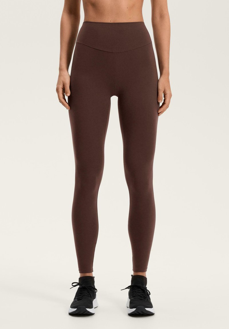 Bruna leggings med hög midja, tillverkade av elastiskt tyg, med en slät textur och en åtsittande design som sträcker sig till anklarna.