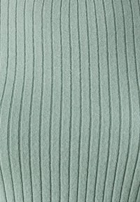 Ribbed fabric in soft green, featuring vertical lines. The texture appears knit, with a slight stretch and a smooth finish.