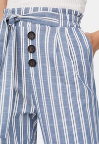 Light blue and white striped pants with a fabric belt, featuring three black buttons on the front and a textured, linen-like material.
