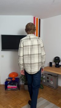 En ternet skjorte i lys beige og brun, med lange ærmer og en afrundet nederkant. Båret med mørke jeans; indendørs med møbler.