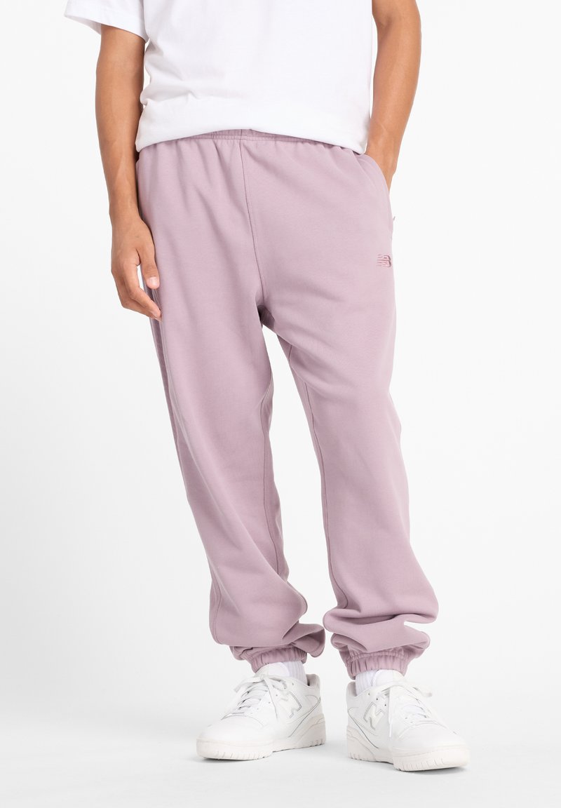 Lavendelfarbene Jogginghosen mit elastischen Bündchen und Bund, ausgestattet mit Seitentaschen und einem kleinen Logodetail. Kombiniert mit weißen Sneakers.