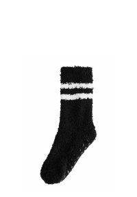 Schwarze flauschige Socke mit weißen Streifen, weicher Textur, Knöchel-Länge und gummierten Punkten auf der Sohle für besseren Halt.