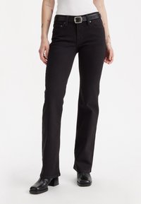 Black denim jeans with a straight-leg cut, featuring a high waist, belt loops, and a leather belt. The material has a smooth texture.