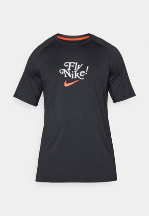 Černé tričko s krátkým rukávem Nike s textem "Fly Nike!" a oranžovým logem swoosh, vyrobené z hladké tkaniny s raglánovými rukávy.