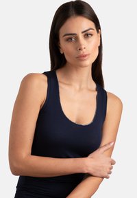 Top in blu navy con scollatura a barca, caratterizzato da un sottile accento argentato lungo il bordo. Realizzato in materiale morbido e aderente.