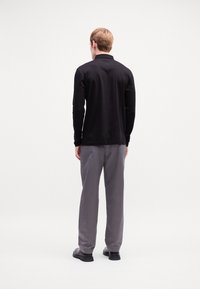 Black long-sleeve shirt with a collar, paired with gray trousers. Simple design, smooth texture, and solid colors without patterns or accents.