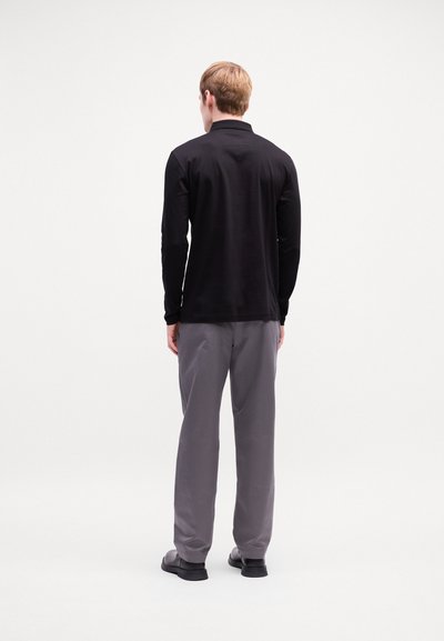 Chemise noire à manches longues avec un col, associée à un pantalon gris. Design simple, texture lisse et couleurs unies sans motifs ni accents.