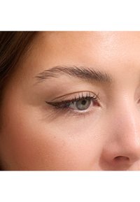 Gros plan sur un œil avec un iris vert, un eyeliner noir bien défini, des sourcils soignés et une texture de peau lisse. Un look maquillage naturel évident.