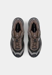 Brown and gray hiking shoes with textured synthetic upper, adjustable bungee laces, and rugged rubber sole. Features branded insole and accents.